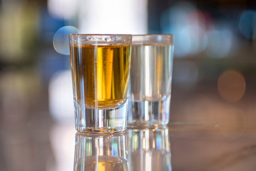 Two glasses of alcohol on a bar.
