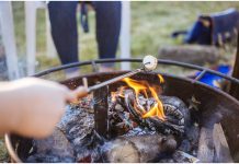 A Guide to Backyard Camping—S’mores Hacks and Campfire Stories Included Image of roasting a marshmallow over campfire