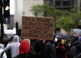 Why You Should Diversify Who You Follow on Social Media Protester holds up sign saying "It's a privilege to educate yourself about racism instead of experiencing it!!!"