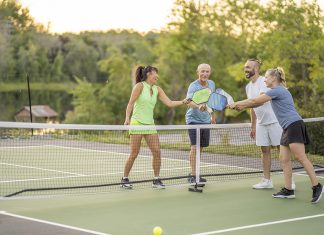 Embrace the Empty Nest: Five Positive Aspects of This Life Transition A group of four adults are seen tapping racquets to show sportsmanship after a Pickleball game together. They are each dressed comfortably in athletic wear and are smiling as they enjoy their time in the fresh air.